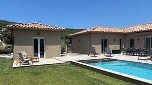 Una propiedad residencial con piscina, dos patios cubiertos y jardín.