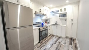 Een moderne keuken met witte kastjes, roestvrijstalen apparatuur en een houten vloer.