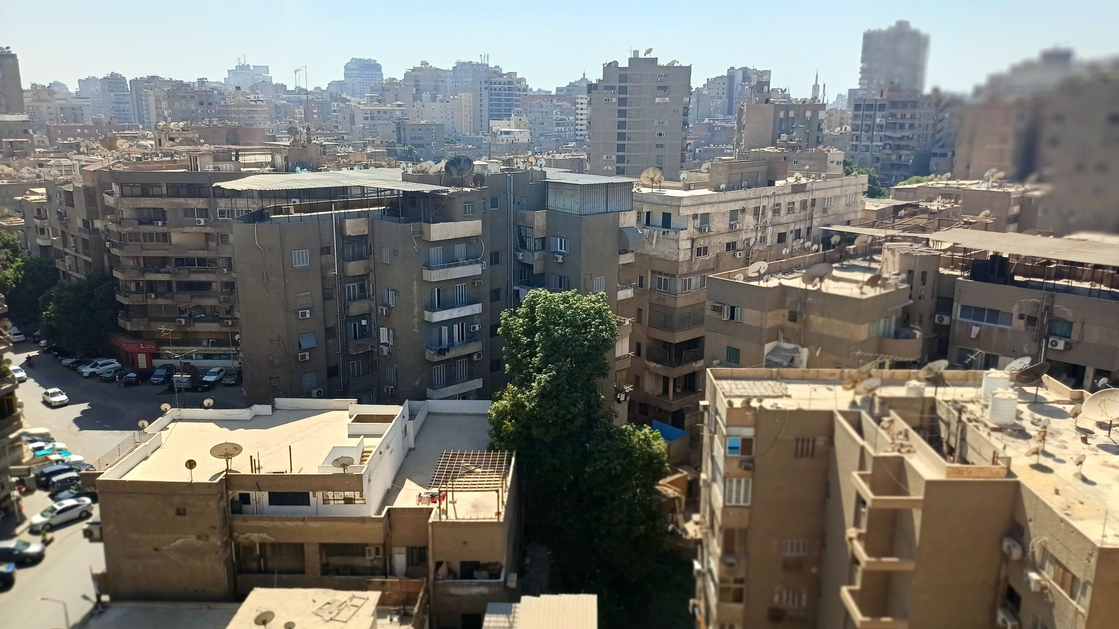A densely packed urban area with multi-story buildings, some with satellite dishes.