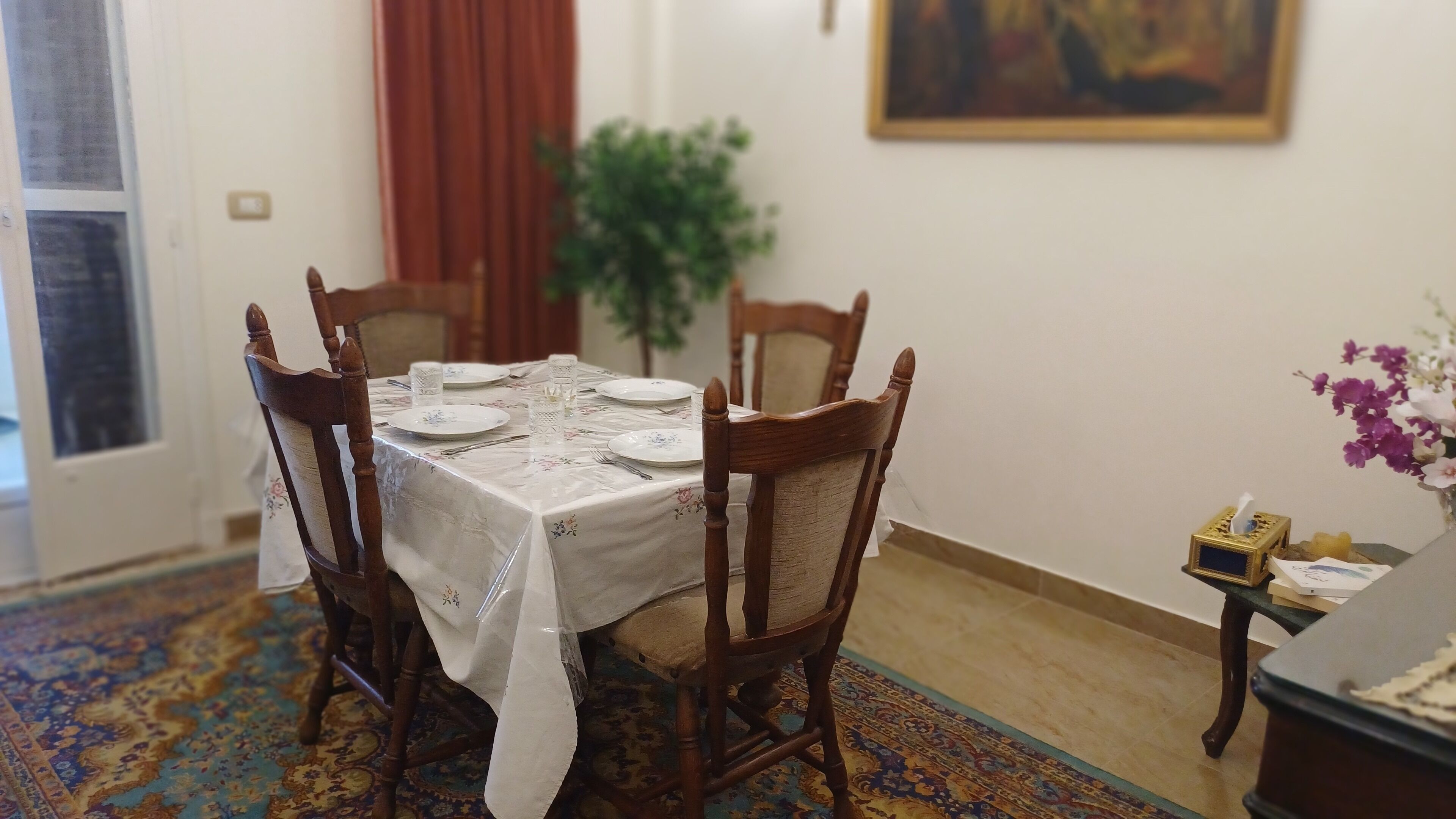Een eethoek met een tafel gedekt voor vier personen, omringd door houten stoelen.