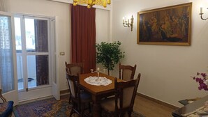 A dining area with a wooden table, chairs, a lace tablecloth, a potted plant, and a painting on the wall. - Elegant 2-Bedroom Apt with City View in Agouza. (Giza Governorate)