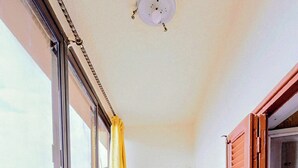 A small balcony with a wicker chair, a table, and a yellow curtain. - Elegant 2-Bedroom Apt with City View in Agouza. (Giza Governorate)