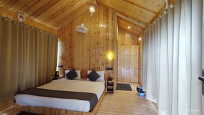 A wooden-paneled bedroom with a large bed, bedside lamps, and a ceiling fan. - Kumaoni Karavan Camps Resort (Nainital)