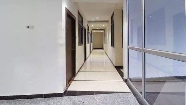 Um corredor comprido e estreito, com portas de um lado e um painel de vidro do outro.