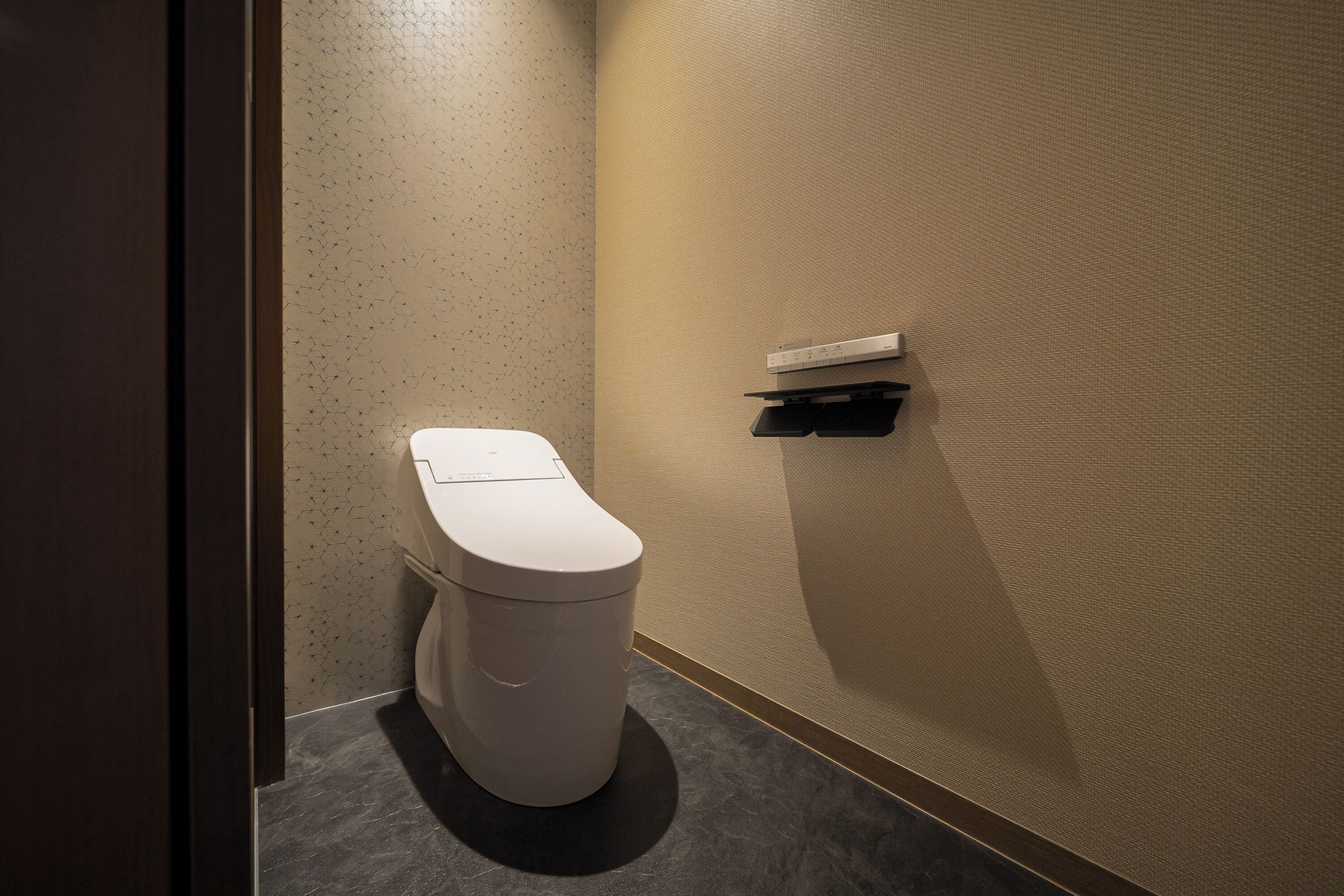 A modern bathroom with a toilet, a towel rack, and a wall-mounted shelf.