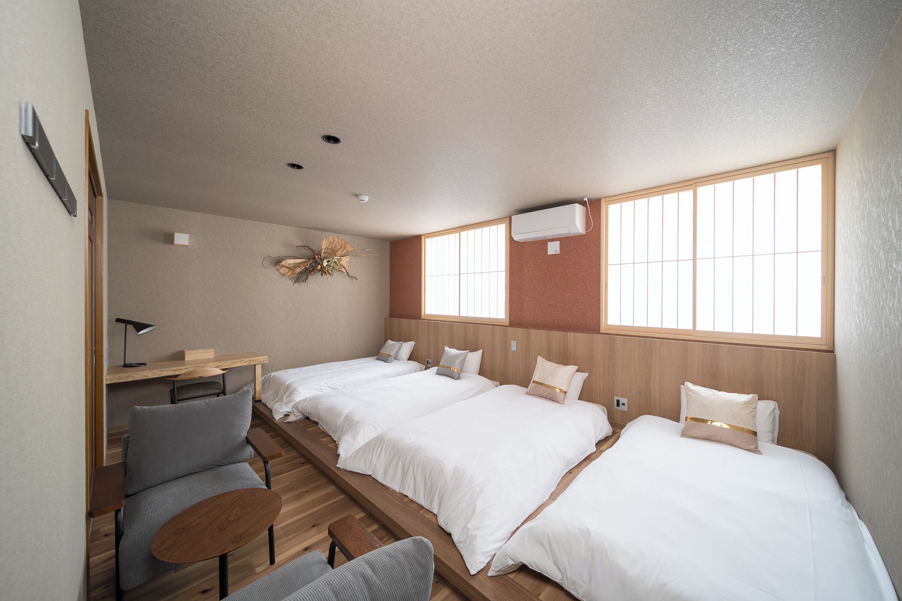 Habitación de hotel con dos camas, un escritorio, una silla y una mesita.
