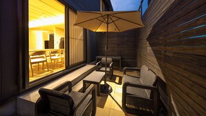 An outdoor patio with wicker furniture, a table, and an umbrella. - TAKENOYADO BEPPU (Beppu)