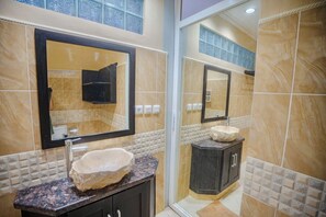 A bathroom with a granite countertop, a stone sink, and a large mirror. - Maria Secret Villa (Sukasada)