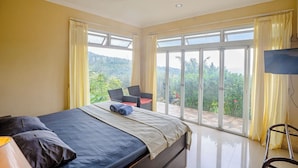 Una camera da letto con un letto, una TV e un balcone affacciato sul verde.