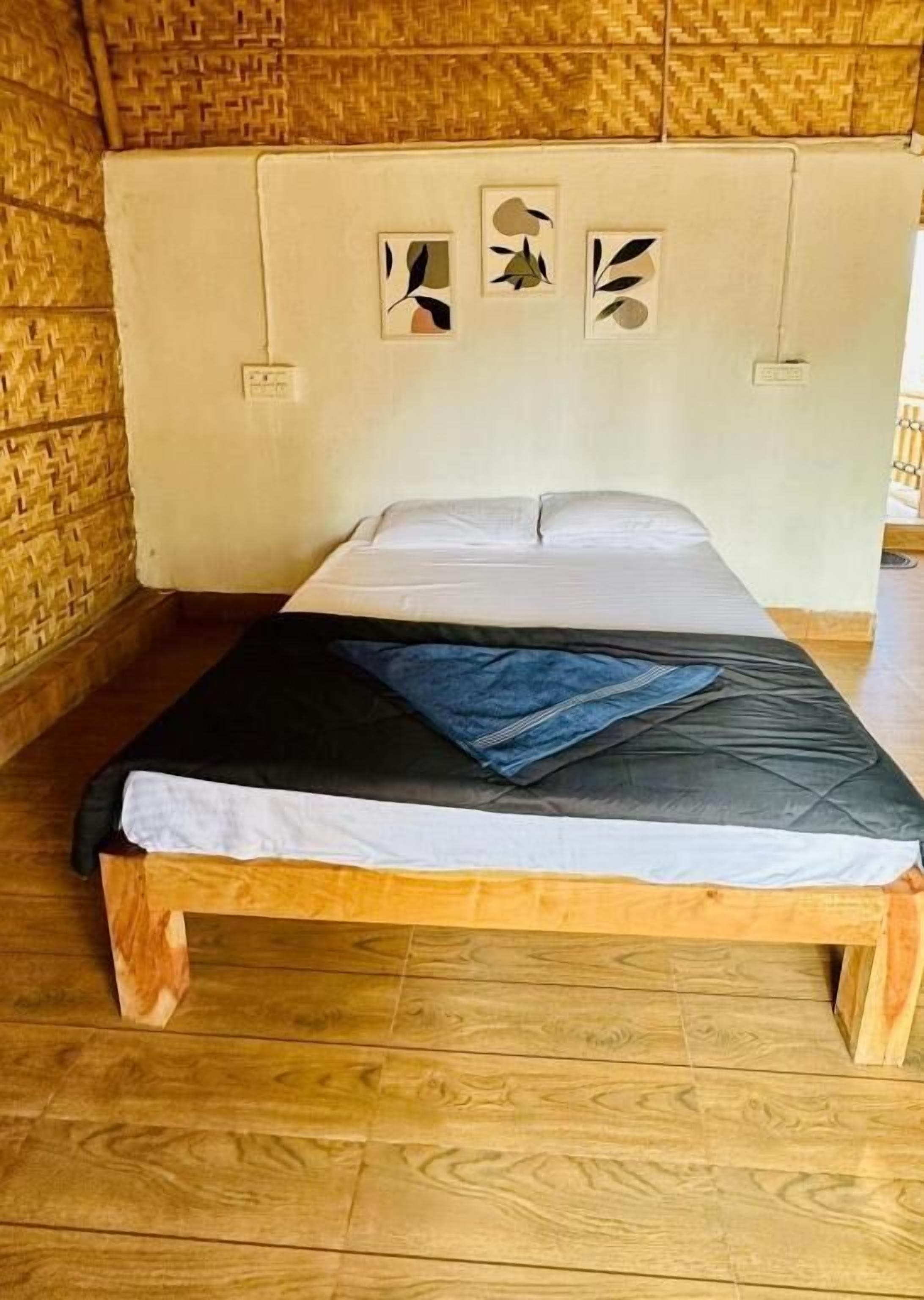 Una cama individual con estructura de madera y colchón, cabecera con diseño trenzado, y suelo de madera.