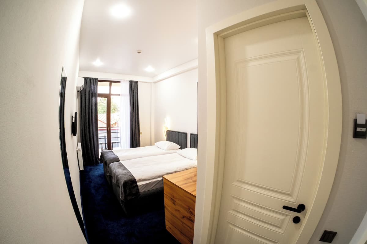 Una camera d'albergo con un letto grande, una cassettiera in legno e una porta.