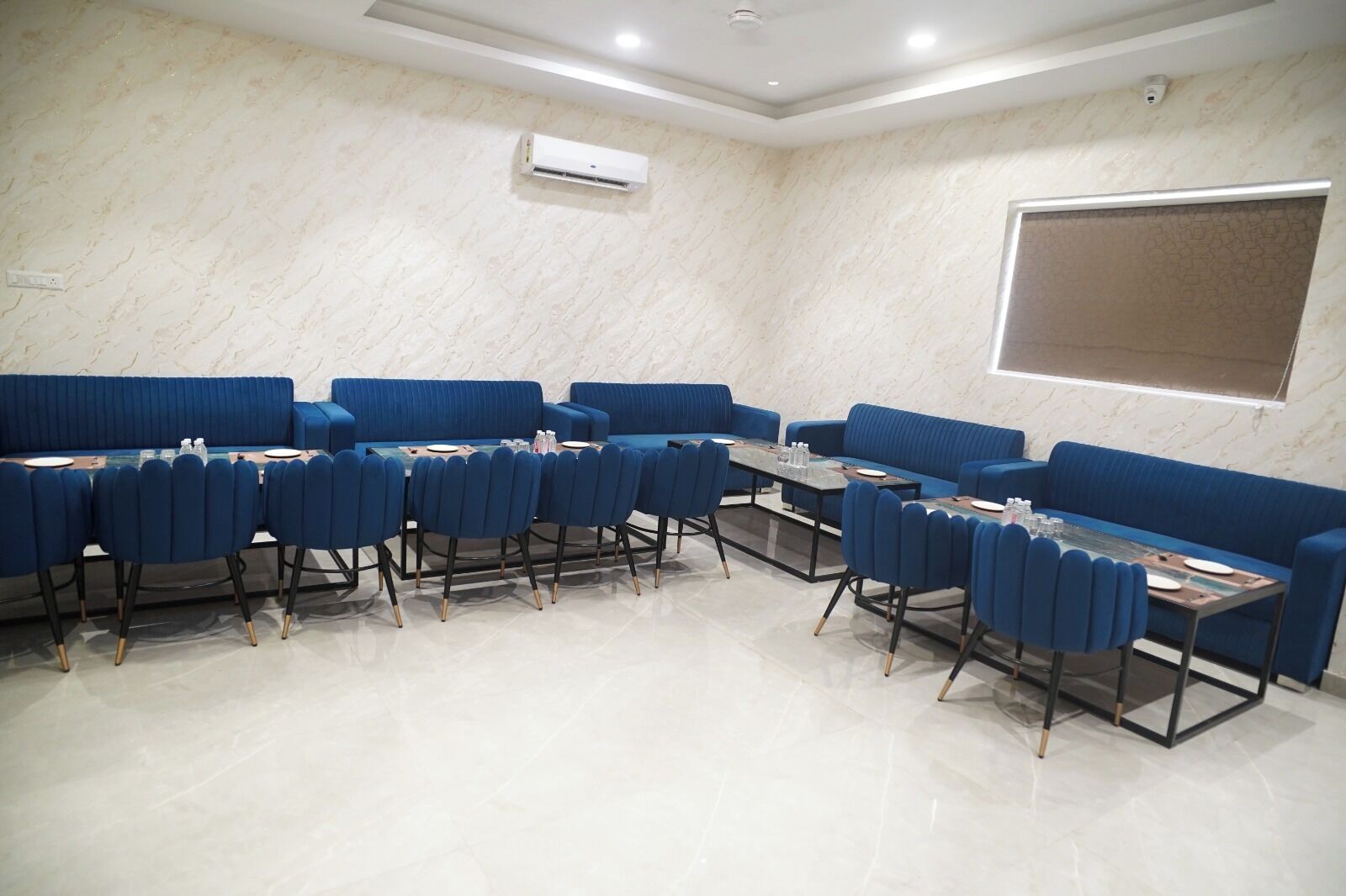 Una sala conferenze con divani e poltrone rivestite in blu, una parete con decoro marmorizzato e un condizionatore d'aria a parete.