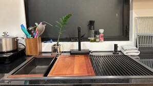 A kitchen with a sink, a cutting board, a plant, and various kitchen utensils. - Marvelous 3-bedroom house with AC in Inglewood (Inglewood)