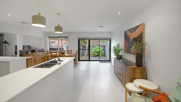 Een moderne keuken met een centraal eiland, houten kastjes en hanglampen.