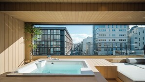 A modern balcony with a hot tub, wooden flooring, and a view of city buildings. - MOKU Kyoto (Kyoto)