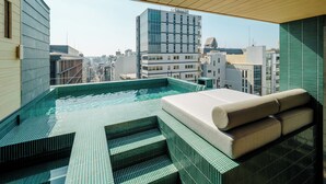 A rooftop infinity pool with a view of the city skyline, a wooden ceiling, and a seating area with cushions. - MOKU Kyoto (Kyoto)