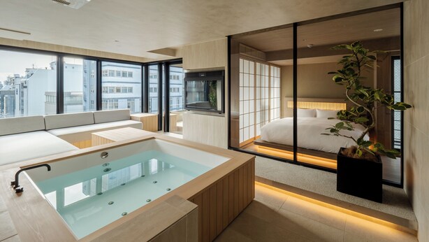 A modern bathroom with a glass-enclosed bathtub, a large window, and a view of the city. - MOKU Kyoto (Kyoto)