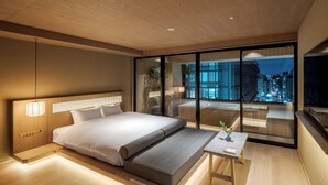 A modern bedroom with a large bed, bedside tables, and a view of a cityscape through floor-to-ceiling windows. - MOKU Kyoto (Kyoto)