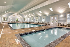 Ein Hallenbad mit deutlichen Fahrbahnen, einem gefliesten Boden und einer Decke mit Dachfenstern.