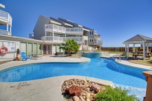 Piscina com placa de proibição de mergulho, boia salva-vidas e um gazebo.