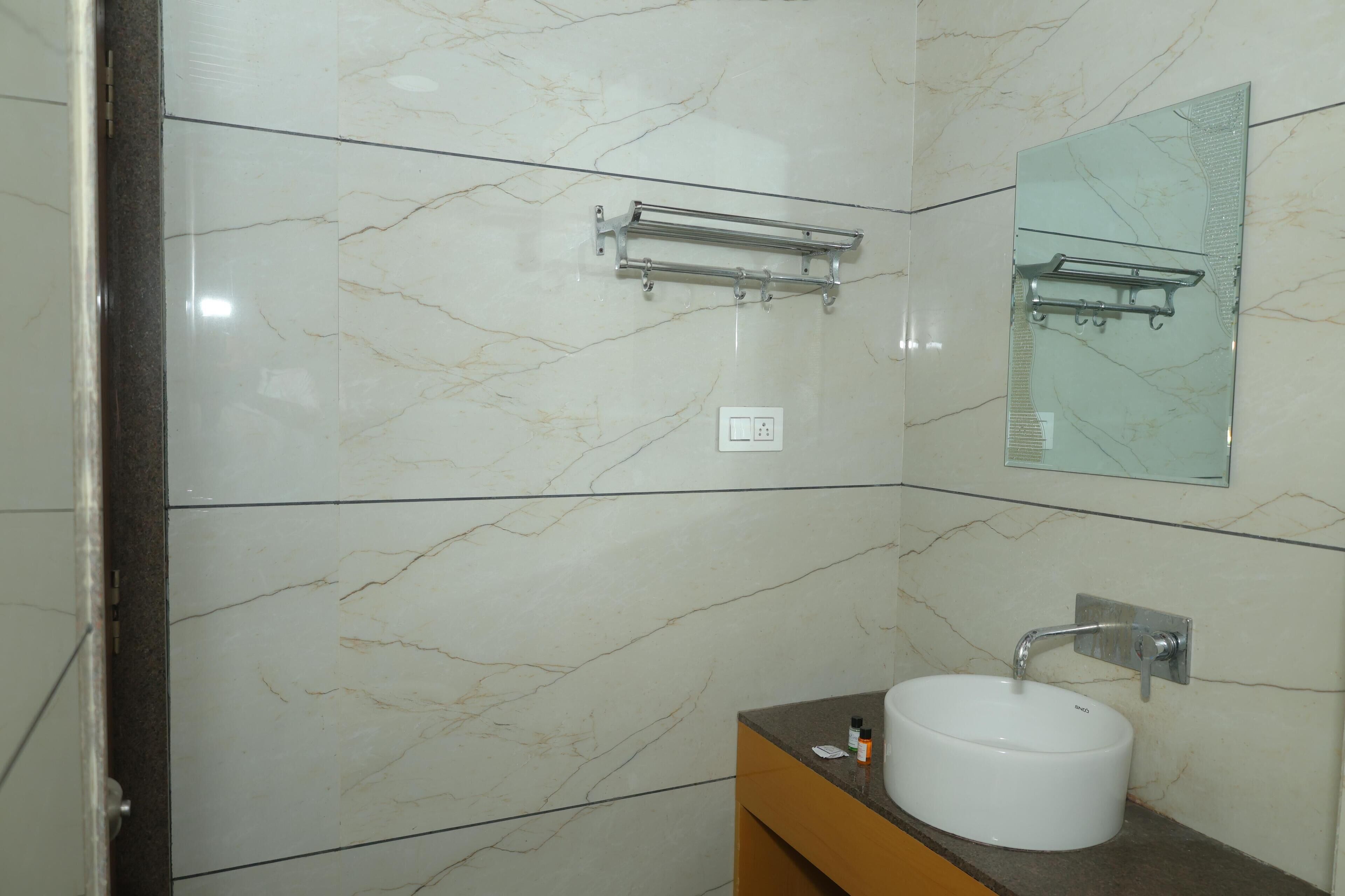Ein Badezimmer mit Marmorwand, einem Waschbecken mit Wasserhahn und einem Handtuchhalter.