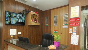 A reception area with a wooden interior, a reception desk, multiple monitors, and a sign indicating check-in and check-out times. - Hotel Kashi Inn (Jodhpur)