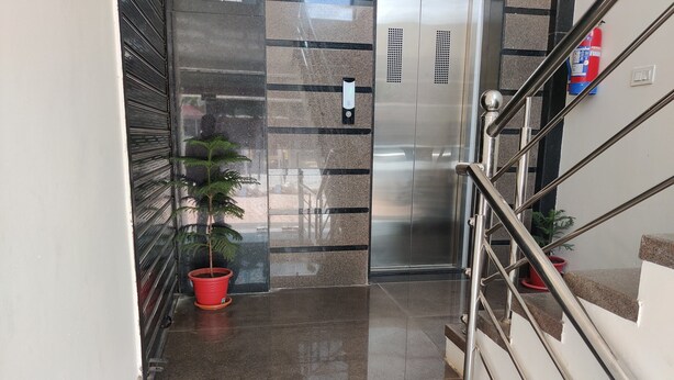 A polished marble staircase with metal railings, a potted plant, and a fire extinguisher on the wall. - Hotel Kashi Inn (Jodhpur)