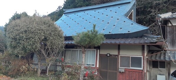 Un edificio tradicional con techo de tejas azules, rodeado de árboles y vegetación.