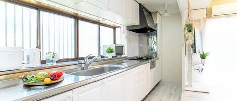 Een koelkast, een magnetron, een kookplaat, kookgerei, borden en bestek