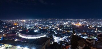 Un paisaje urbano nocturno con un estadio y edificios circundantes.