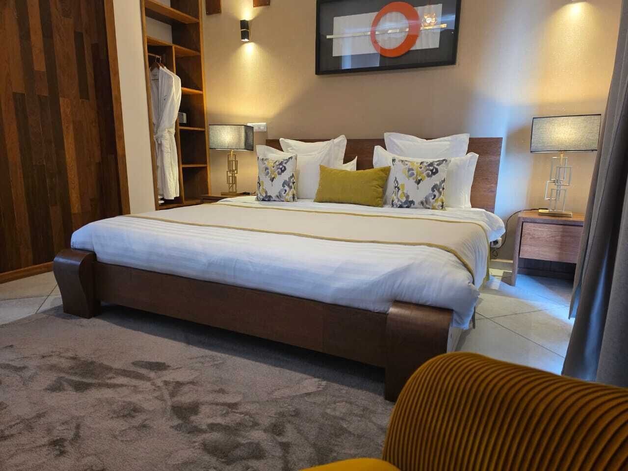 A hotel room with a large bed, a wardrobe, a bedside table, and a wall-mounted artwork.
