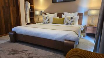 A hotel room with a large bed, a wardrobe, a bedside table, and a wall-mounted artwork.