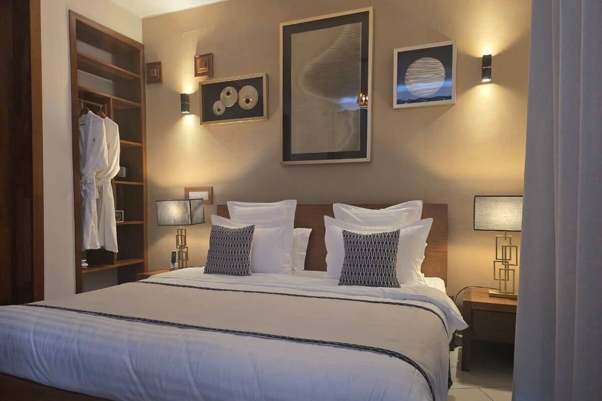 Een hotelkamer met een groot bed, een kledingkast en kunstwerken aan de muur.