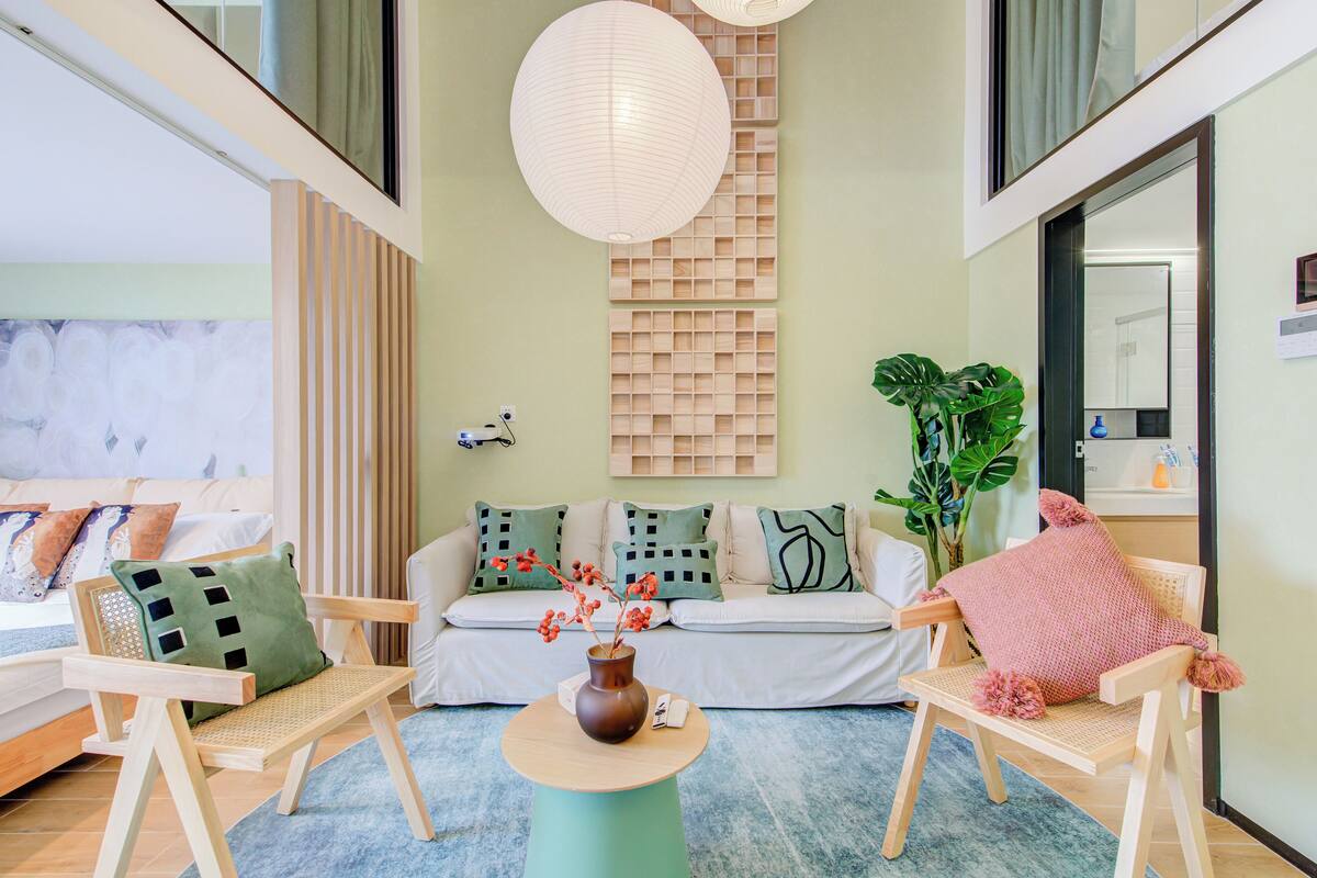 Ein modernes Wohnzimmer mit einer Couch, zwei Holzstühlen, einem Couchtisch und einer großen Pflanze.