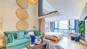 Quarto de hotel moderno com cama grande, sofá, mesa de centro e varanda com vista.