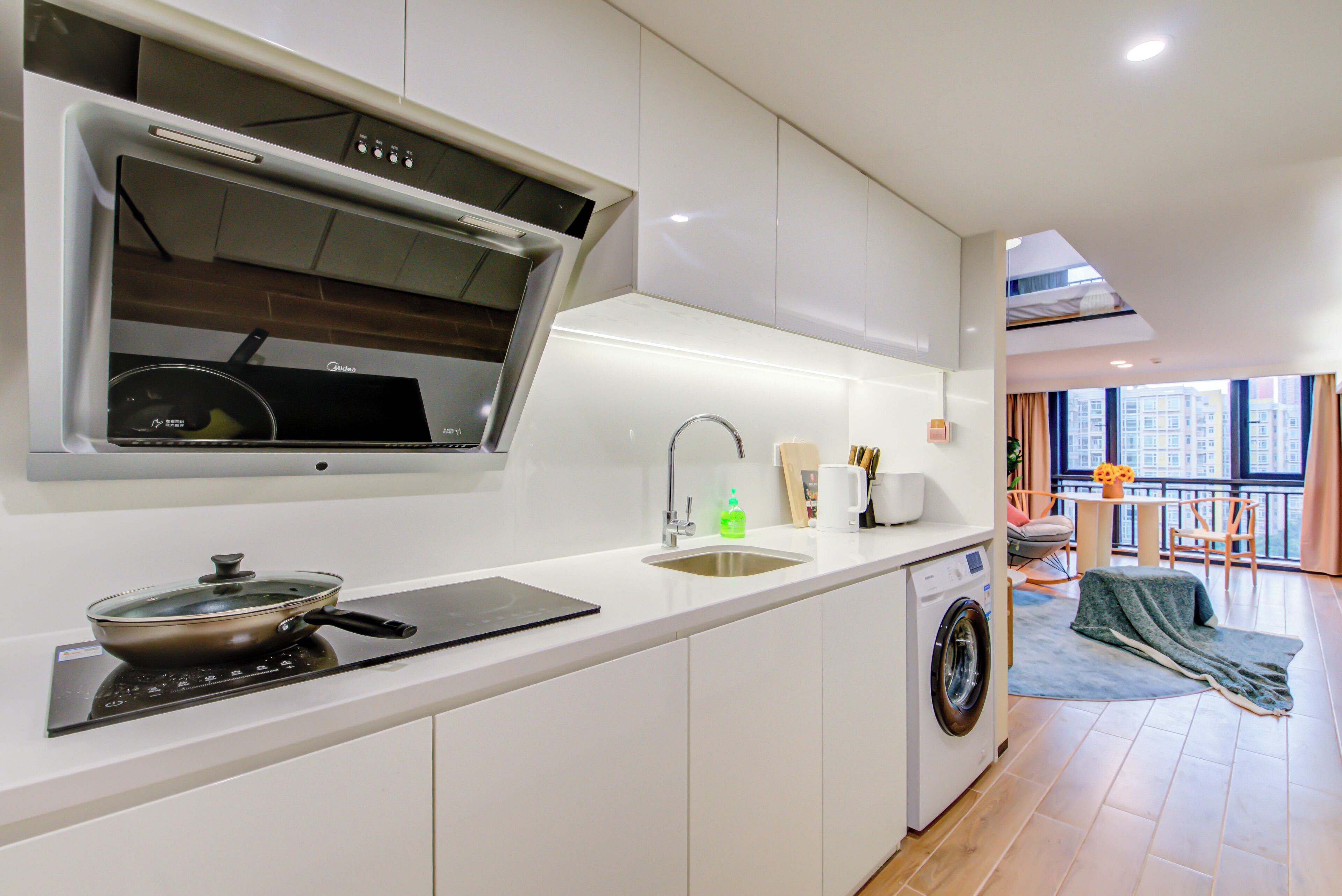 A modern kitchen with a built-in stove, sink, and washing machine.