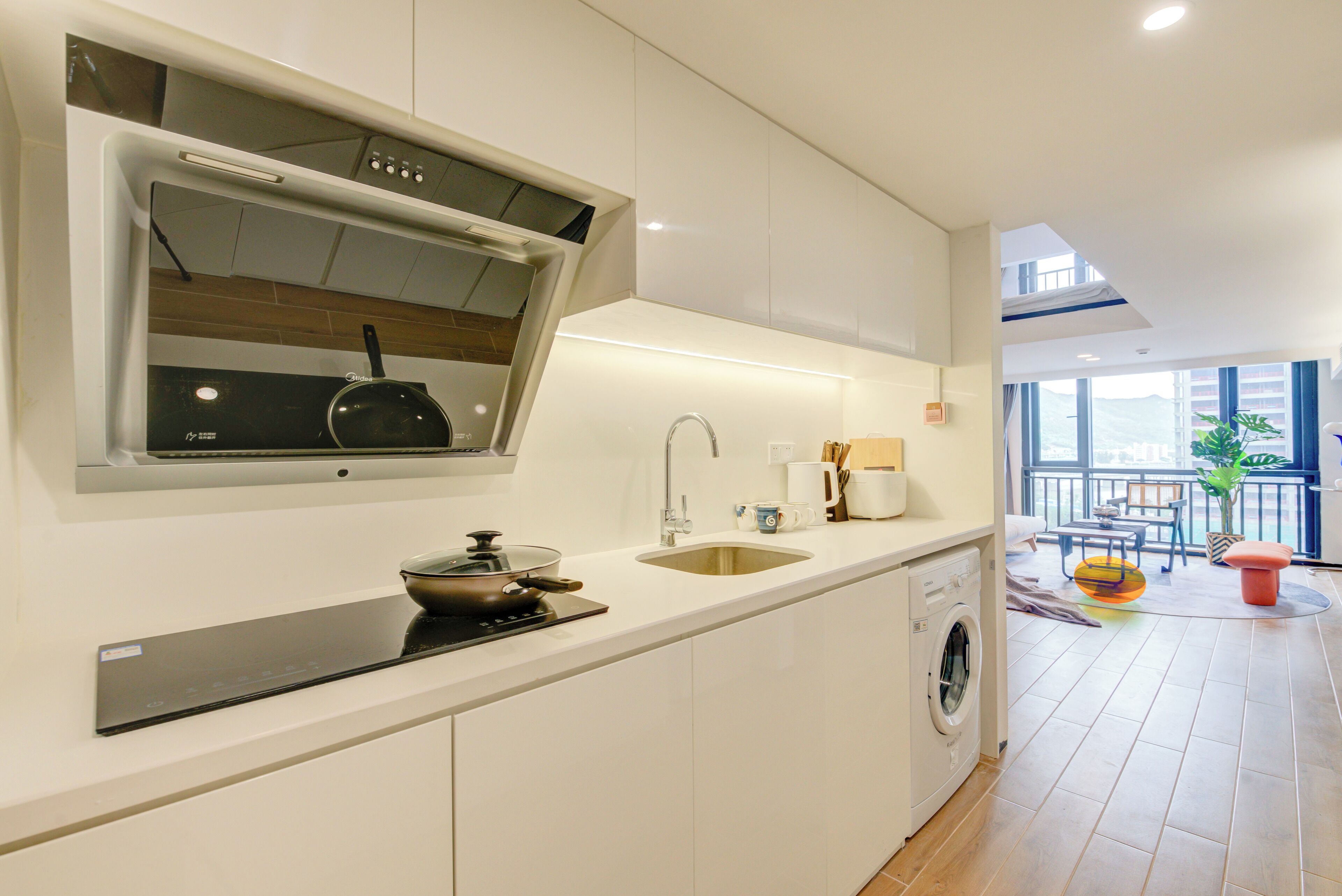A modern kitchen with a built-in oven, a sink, and a washing machine.