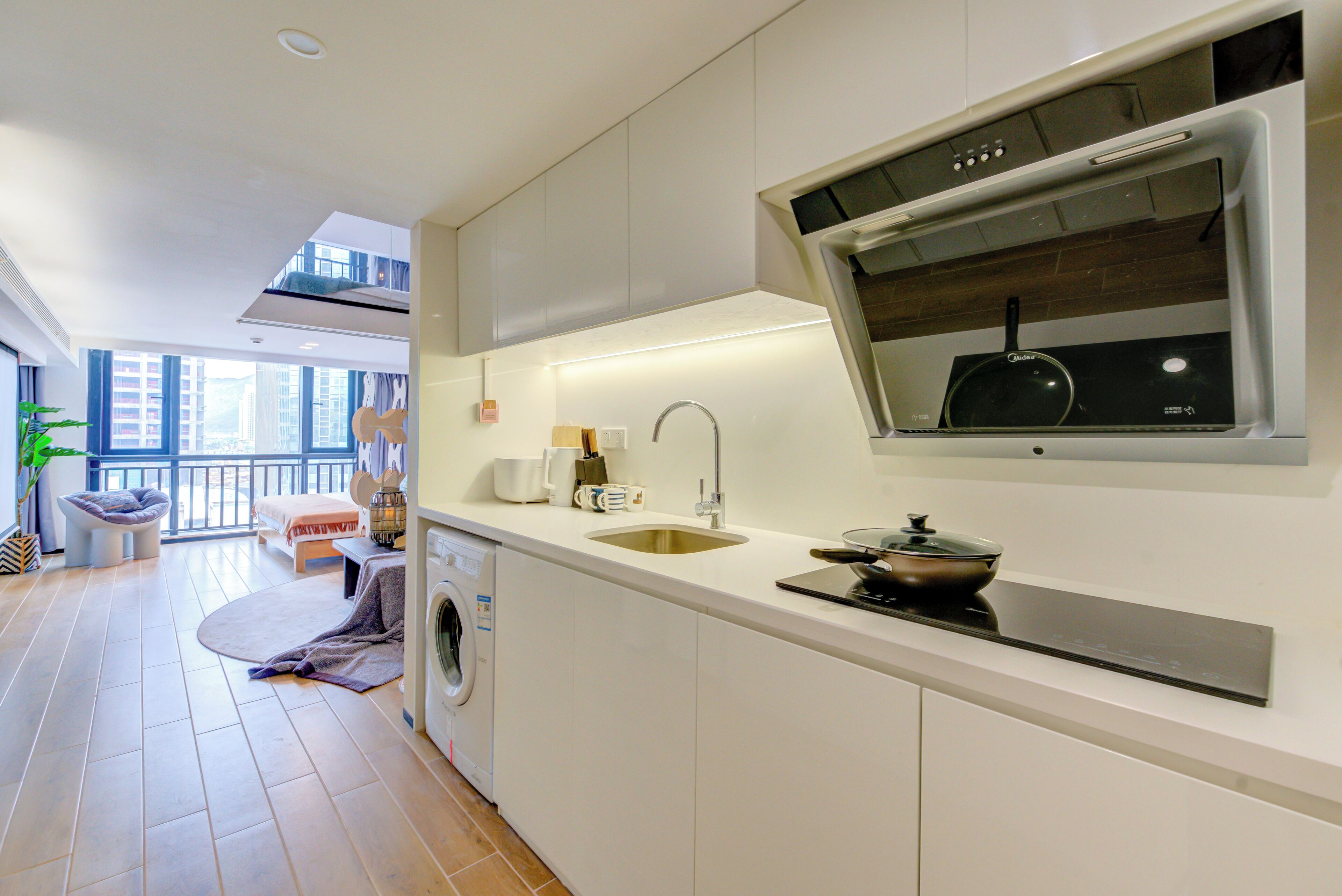 A modern kitchen with a built-in oven, a sink, and a window overlooking the city.