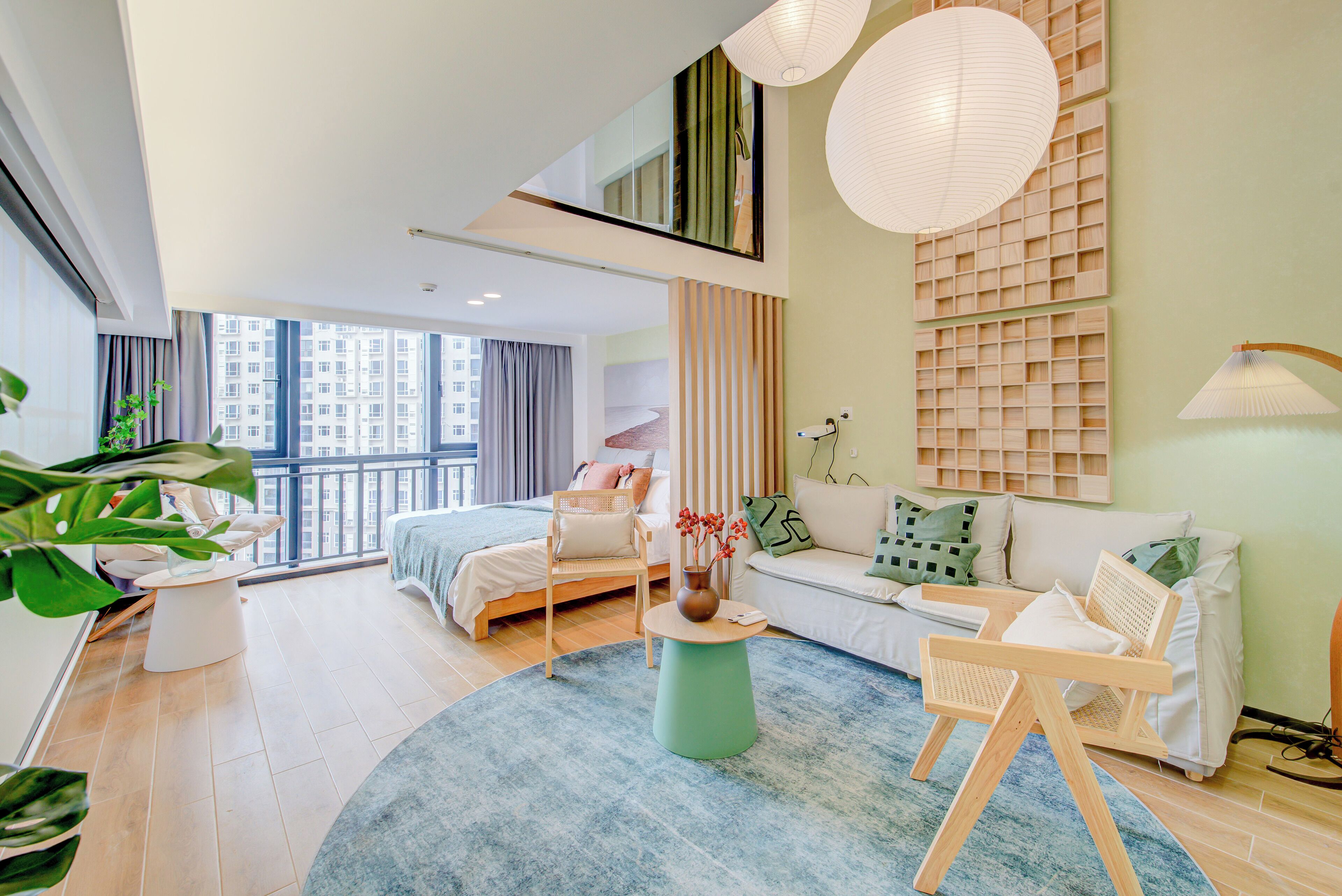 Une chambre d’hôtel moderne avec une grande fenêtre, un lit, un canapé, une table basse et un fauteuil.