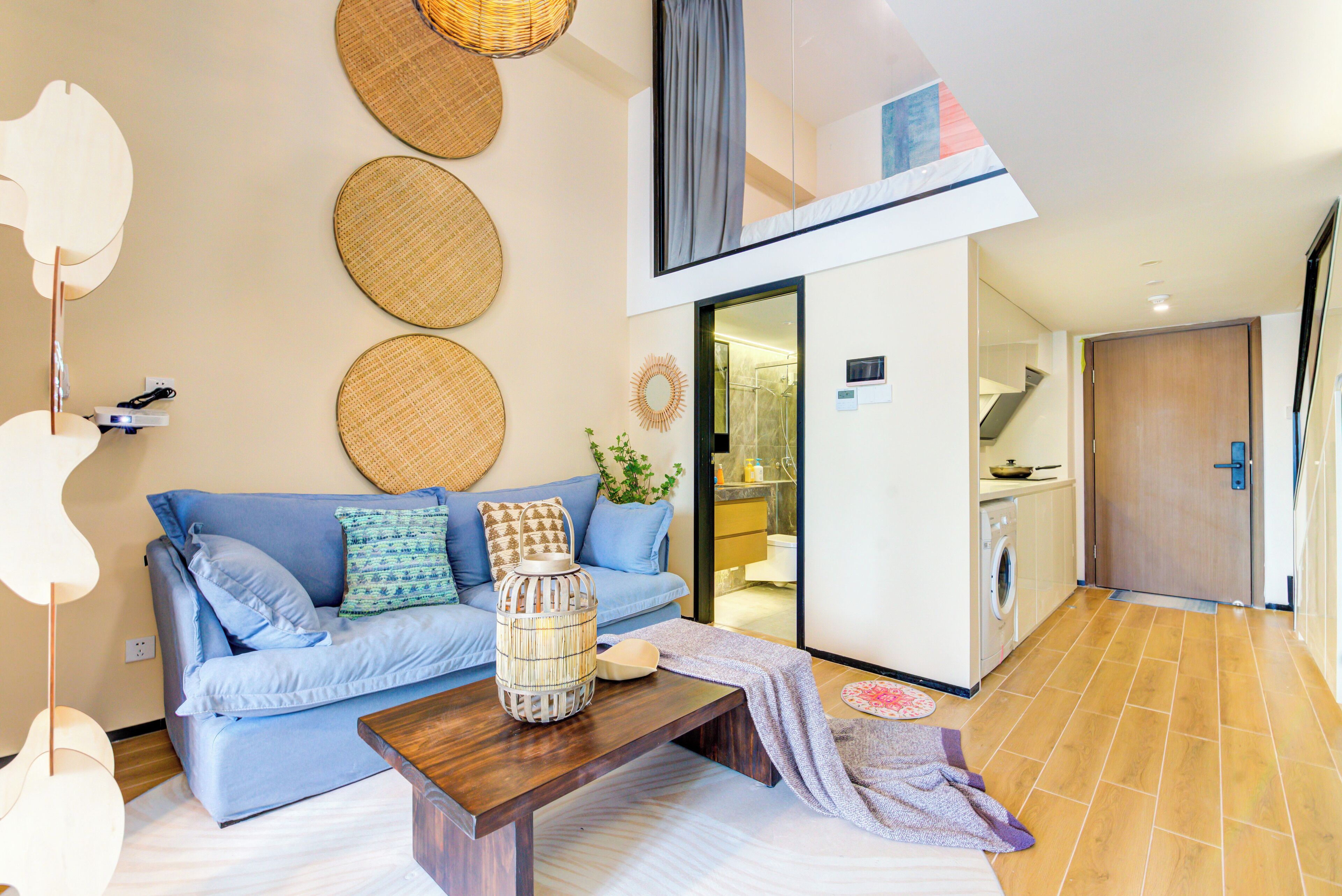 A modern living room with a blue sofa, a wooden coffee table, and woven wall decorations.