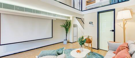 A modern living room with a sofa, a coffee table, and a TV screen.