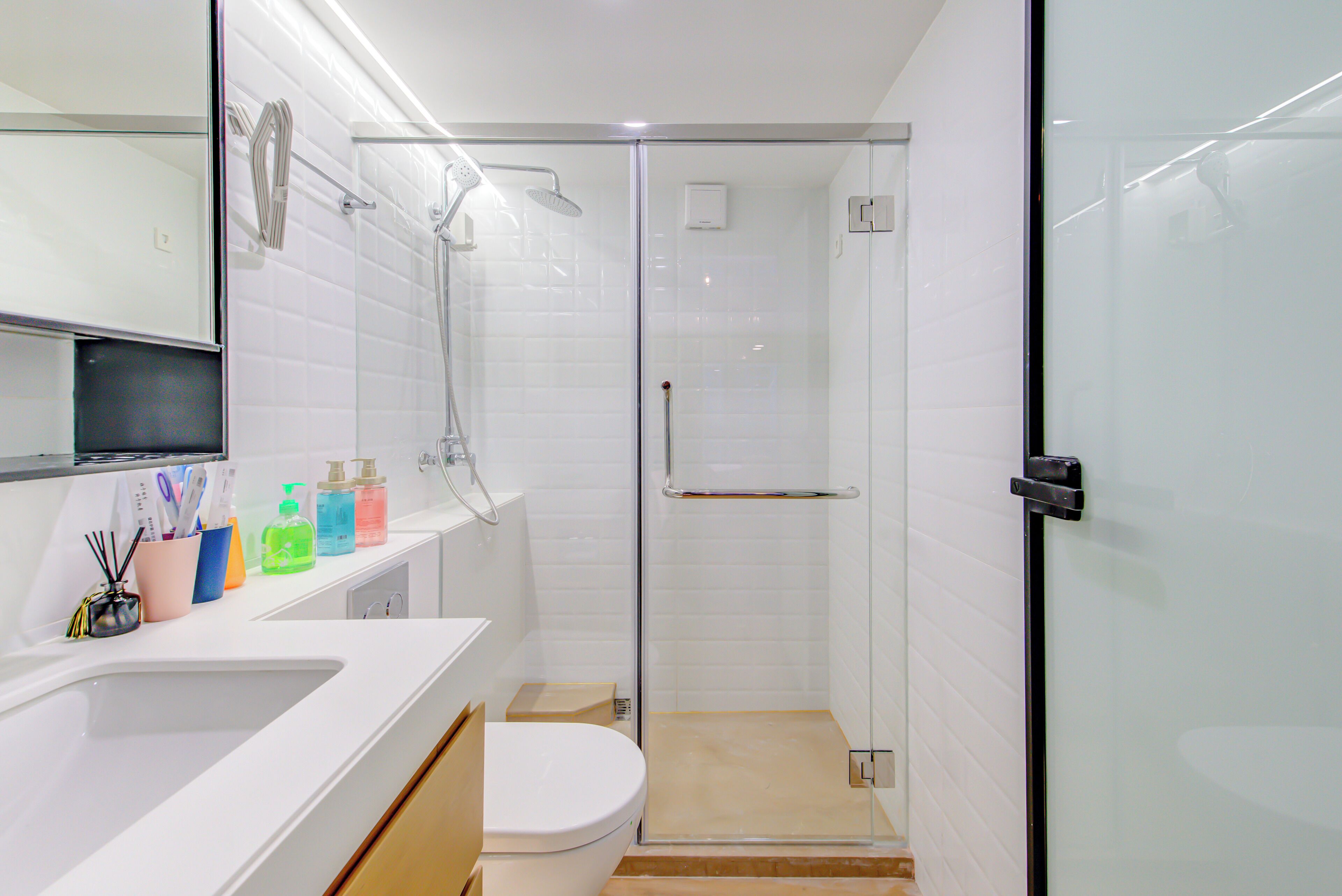 A modern bathroom with a glass shower enclosure, a white sink, and a toilet.