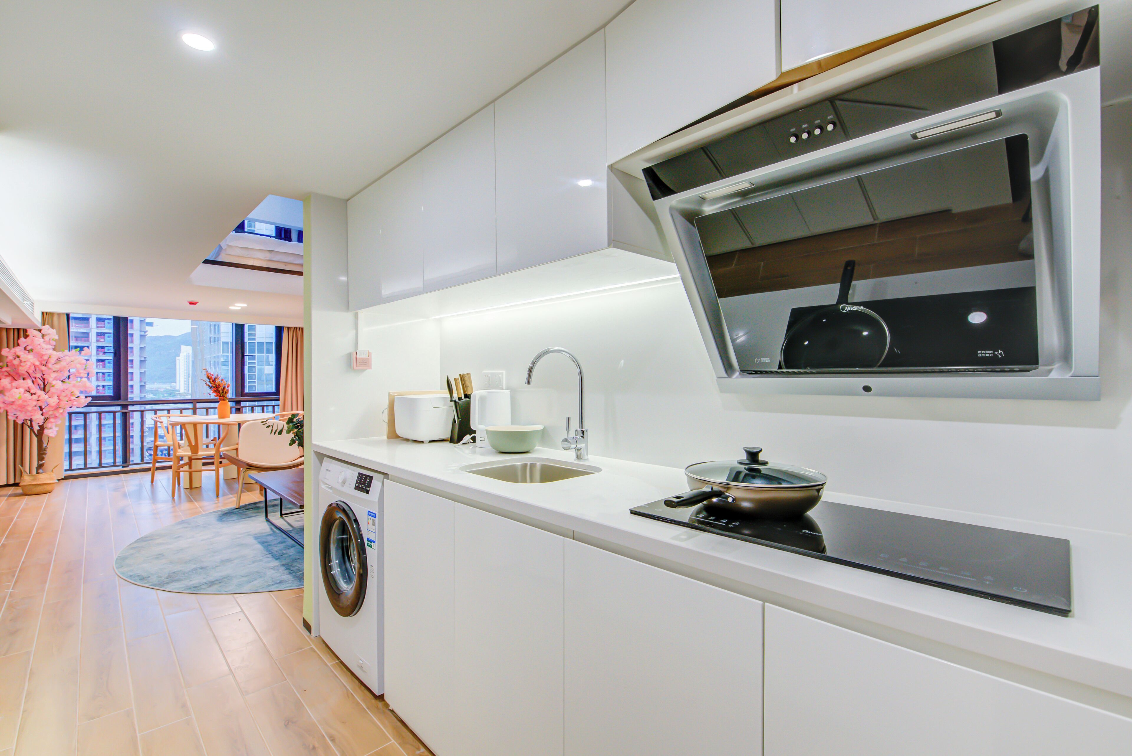 A modern kitchen with a built-in oven, a sink, and a window overlooking a balcony.
