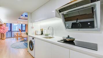 A modern kitchen with a built-in oven, a sink, and a window overlooking a balcony.