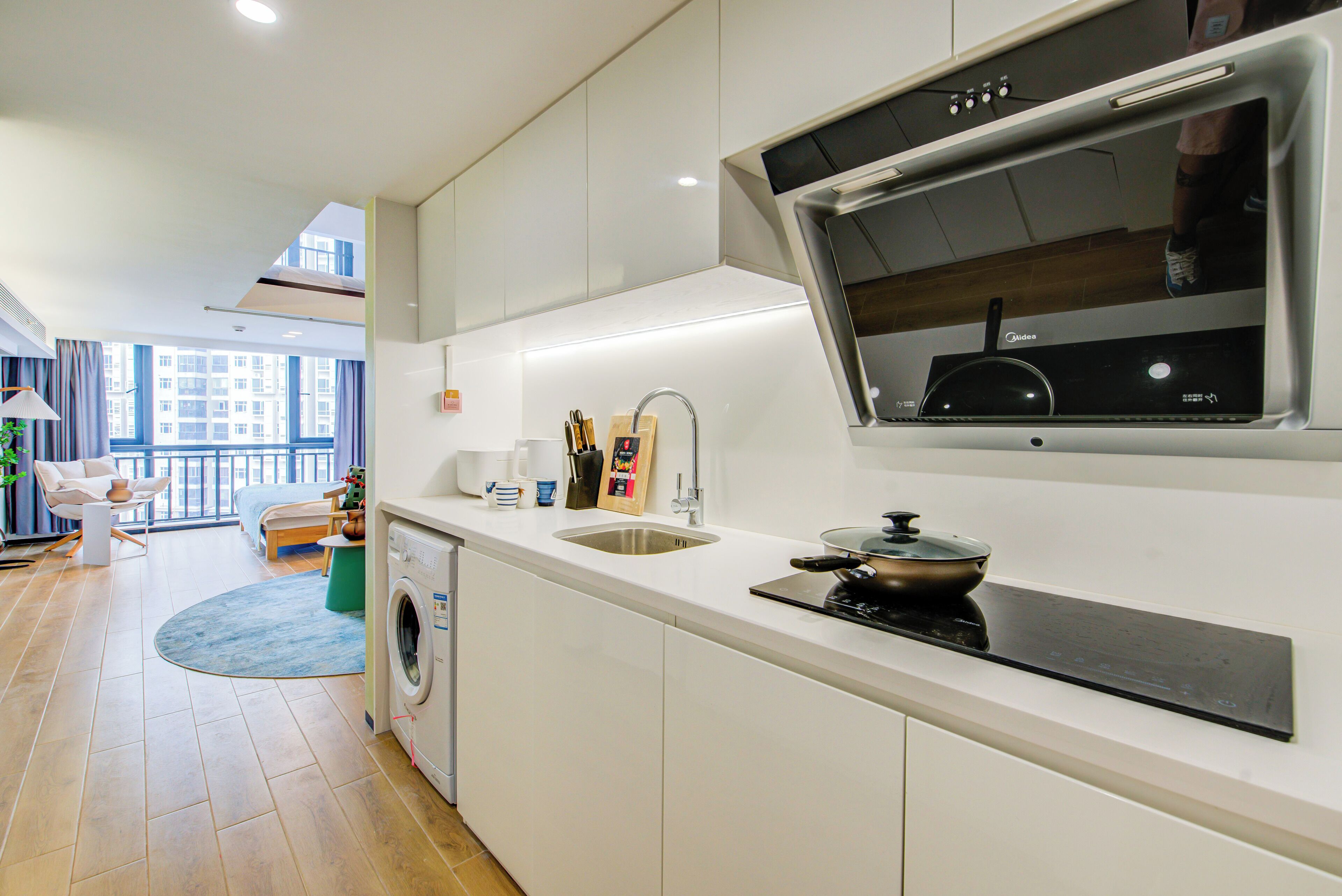 A modern kitchen with a built-in oven, a sink, and a window overlooking the city.