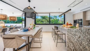 Una cocina moderna con una isla grande, taburetes de bar y un comedor con mesa y sillas.