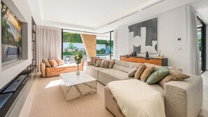 Una sala moderna con un amplio sofá modular, una mesa de centro y un televisor.