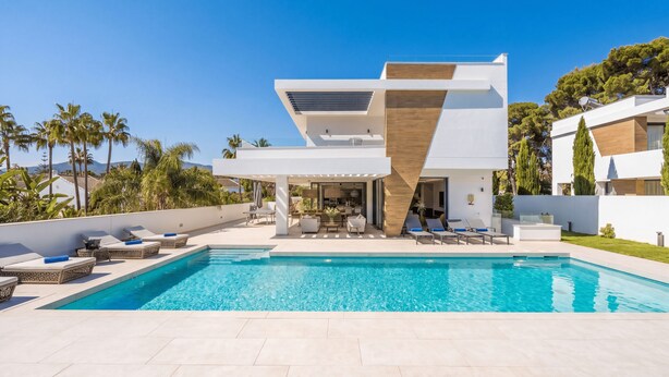 Una casa moderna con piscina, mobiliario exterior y vistas a palmeras.