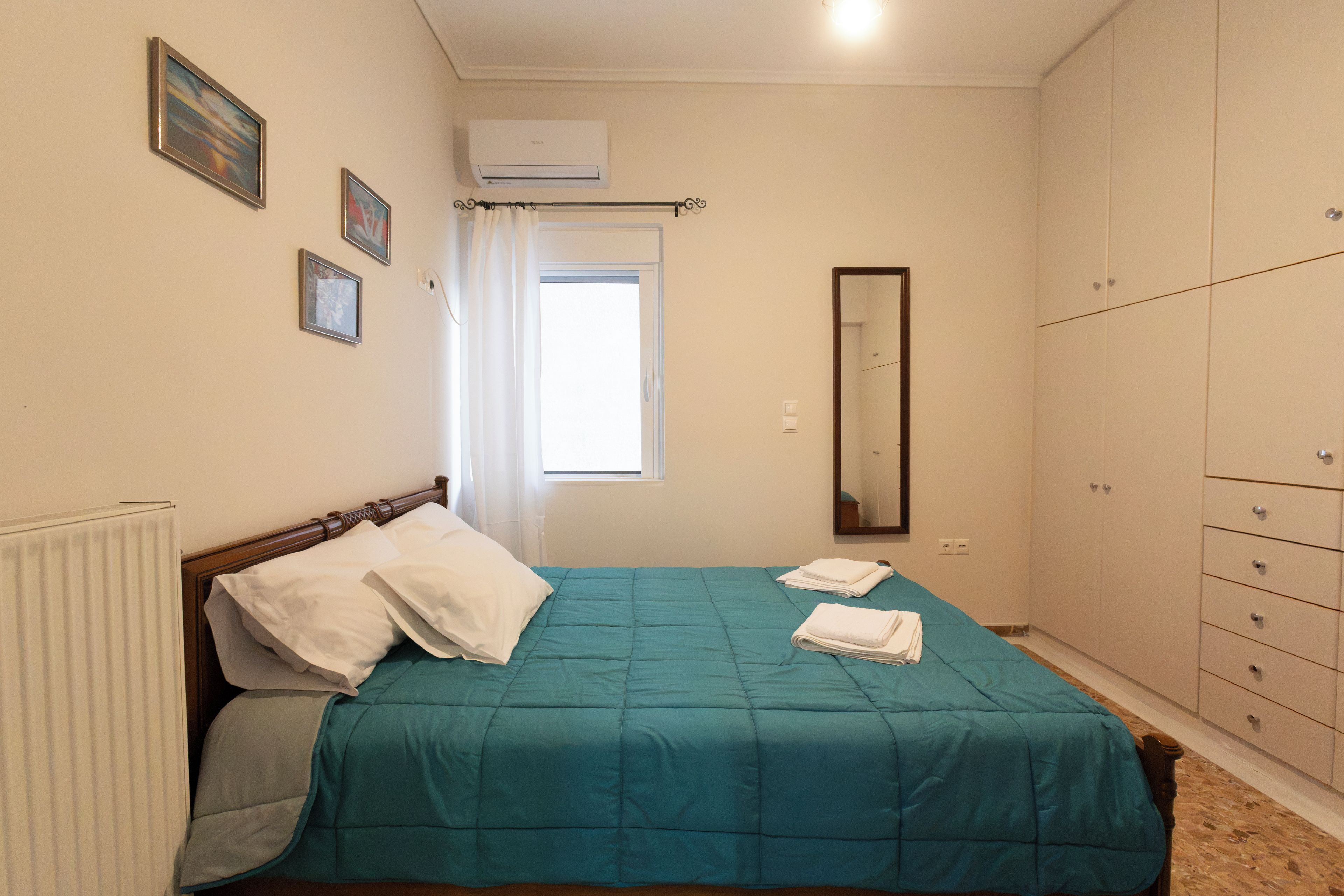 Une chambre à coucher avec un lit, une fenêtre, un miroir et une armoire.
