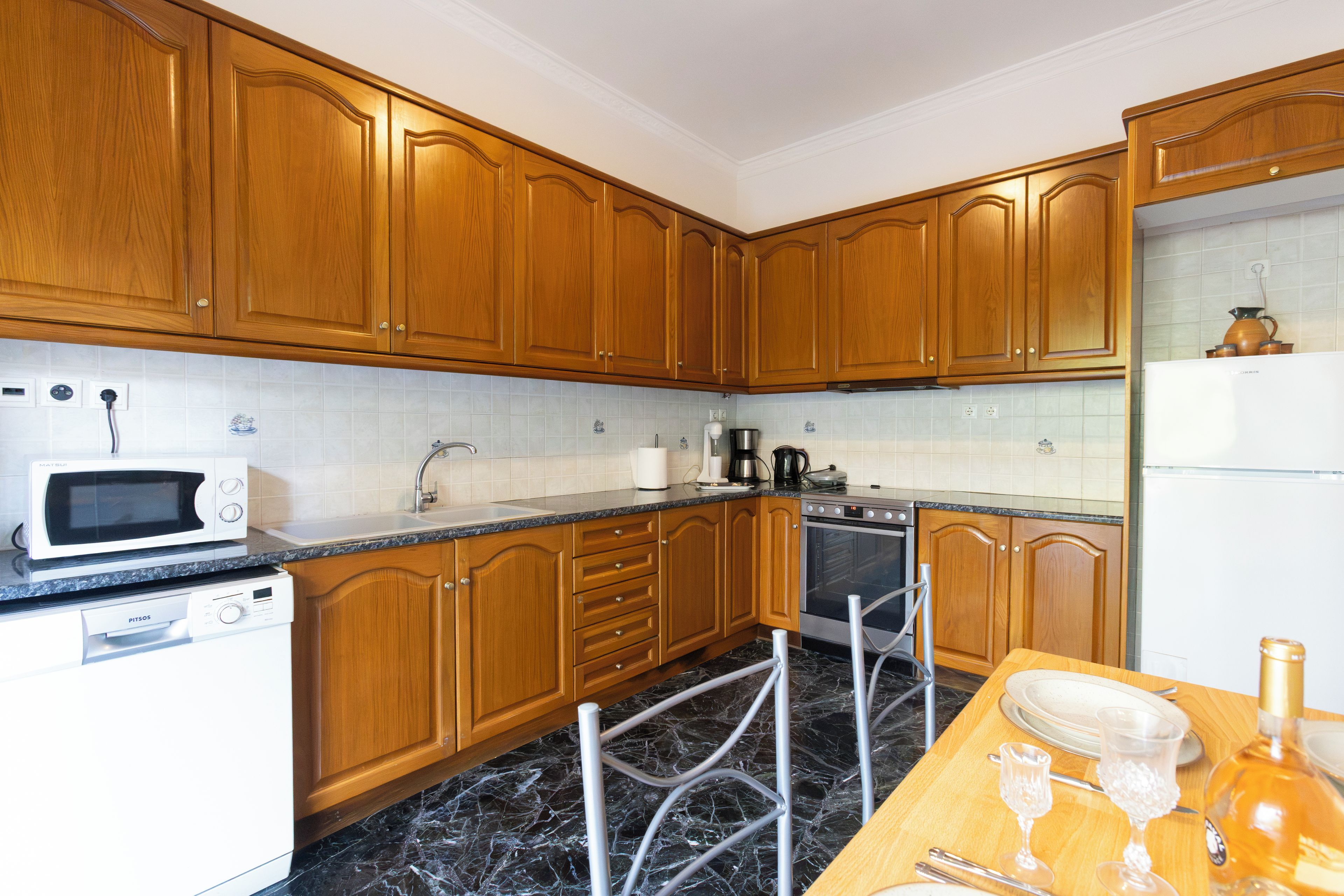 A kitchen with wooden cabinets, a microwave, a sink, and a dining area with a table set for two.